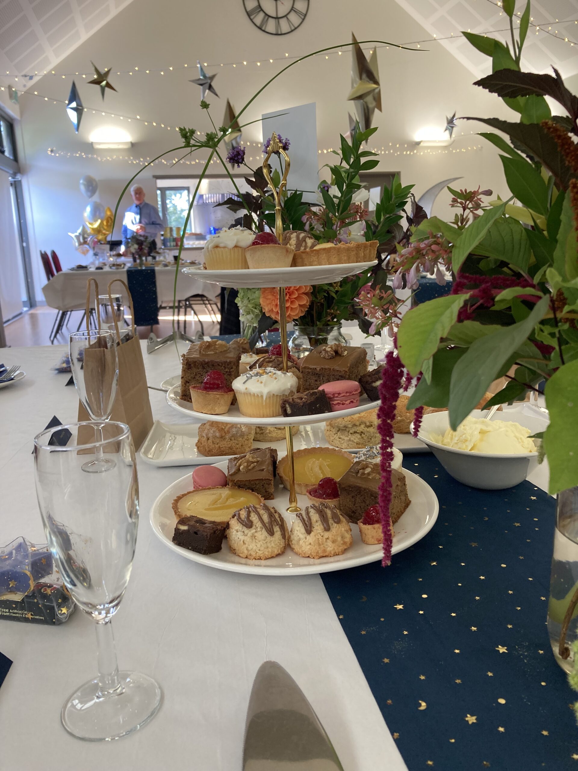 A table set with plates of cake stacked and flowers, for a gathering or celebration